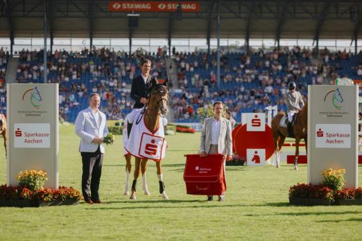 Foto: Das Foto zeigt den Sieger des Auftaktspringens im Sparkassen-Youngsters-Cup beim CHIO Aachen 2025, Steve Guerdat auf Lusso Gih Z, gemeinsam mit Dr. Christian Burmester (Stellvertretender Vorstandsvorsitzender der Sparkasse Aachen) und ALRV-Aufsichtsratsmitglied Dr. Stephan Kranz - Fotograf: CHIO Aachen/Diana Wahl