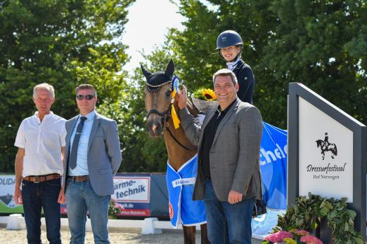 Foto: Der strahlenden Siegerin in der Kuschel Cup-Etappe beim Dressurfestival Hof Norwegen, Theresa Waitz und ihrem Cosmo de Luxe WE, gratulierten Hauptsponsor Alexander Kuschel (r.), Richter Stephano Enrico Blasi und Gastgeber Markus Waterhues (l.) - Fotograf: RathmannVerlag/Malina Blunck