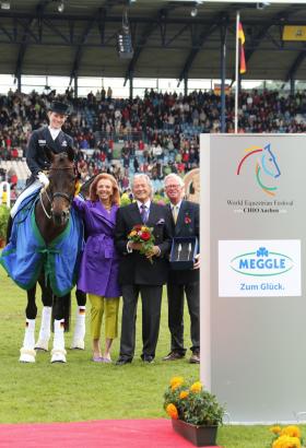 Foto: Helen Langehanenberg. Es gratulieren von rechts Baron Wolf von Buchholtz, Vizepräsident des Aachen-Laurensberger Rennvereins, sowie Toni und Marina Meggle.