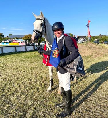 Foto: Schimmel Clooney ist ein Siegertyp, sein Reiter auch: Peter Jakob Thomsen mit Fehmarn-Flagge und breitem Lächeln. Binnen 14 Tagen bereits der zweite Sieg in einem schweren Springen - Fotograf: Julia Kujaw