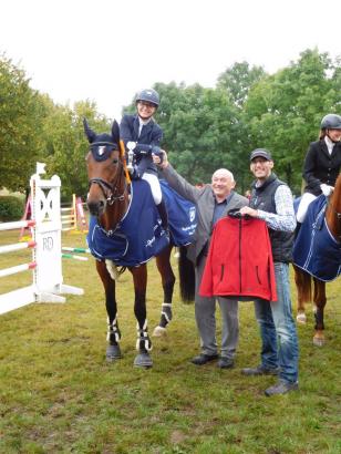 Foto: Der strahlenden Siegerin des Stil-L, Florence Hirsch, gratuliert der Organisator der Serie, Rudolf Singer und sie erhält von Alexander Göpfert eine Softshell-Jacke der Firma ChampionRider, Rielingshausen.