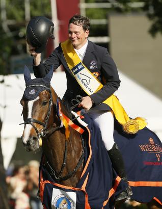 Foto: Wenn die goldene Schärpe flattert, freut sich der Springprofi: Toni Haßmann, der Sieger im Großen Preis von Wiesbaden, auf Classic Man - Fotograf: WRFC,Toffi