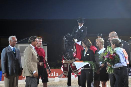 Foto: Siegerin Kristina Sprehe auf Desperados, unter den Gratulanten sind der Vorsitzende des Dressur-Ausschusses der Internationalen Reiterlichen Vereinigung, Trond Asmyr (ganz li.), Hausherr Prof. Edwin Kohl (2. v. li), Bundesumweltminister Peter Altmaier (re.) und Hausherrin Arlette Jasper-Kohl (2. von re.) - Fotograf: a-focus altenhofer