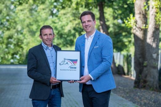 Foto: Markus Scharmann, Turnierleiter der Bundeschampionate, und Jonas Niemeyer, Geschäftsführer der HKM Sports Equipment GmbH, präsentieren das Logo der HKM Bundeschampionate - Fotograf: FN