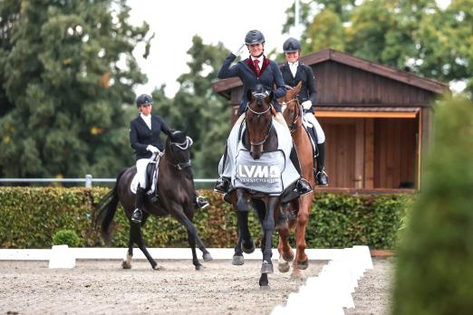 Foto: Grüßt fröhlich und formvollendet - Stephanie Fiedler (HuLG Neustadt-Dosse) auf dem Sieger Belantis II. Dahinter die Platzierten Xulia Pantskhava/ Belisimo und Sophie Delaunay/ Bernay`s Son - Fotograf: ACP Andreas Pantel