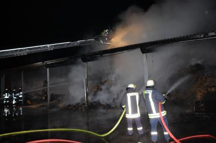 Feuerwehrleute bekämpfen das Feuer im Strohlager. Foto: Kimstädt, KFV-Pinneberg 