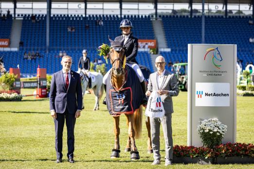 Foto: Das Foto zeigt Alice Laine, die Siegerin im NetAachen-Preis, auf Emerald Sitte. An ihrer Seite Andreas Schneider (Geschäftsführer NetAachen) und ALRV-Aufsichtsratsmitglied Dr. Thomas Förl - Fotograf: CHIO Aachen/Jasmin Metzner