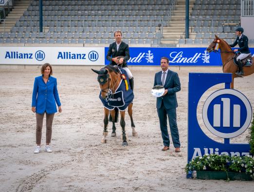 Foto: Dem Sieger gratulieren Oliver Leber, Leitung Vertriebsdirektion Köln der Allianz und Stefanie Peters, Präsidentin des Aachen-Laurensberger Rennvereins e.V.. - Fotograf: Aachen International Jumping/Arnd Bronkhorst.
