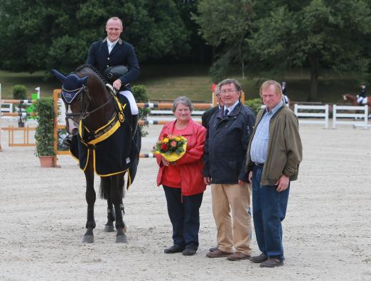 Foto: Schwarz-Goldenene Bänder der Dressur- und Springpferde: Carl, Sieger der fünfjährigen Springpferde mit Tim Hoster. Der Wallach siegte mit der Traumnote von 8,7! Auf dem Foto ist das Züchterehepaar Niethammer und Verbandspräsident Karl-Heinz Eckerlin mit zu sehen - Fotograf: Olav Krenz