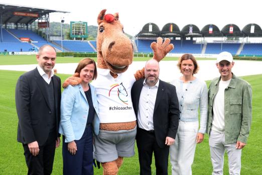 Foto: Das Foto zeigt die Teilnehmer der Pressekonferenz vor dem TSCHIO Aachen 2026: (v.l.) Christopher Ward (Generalmusikdirektor der Stadt Aachen), Birgit Rosenberg (ALRV-Vorstandsmitglied), CHIO Aachen-Maskottchen Karli, Dr. Michael Ziemons (Oberbürgermeister der Stadt Aachen), Stefanie Peters (ALRV-Präsidentin) und Richard Vogel (Anwärter auf den Rolex Grand Slam - Fotograf: Andreas Steindl/CHIO Aachen Foto: Das Foto zeigt die Teilnehmer der Pressekonferenz vor dem TSCHIO Aachen 2026: (v.l.) Christopher Ward (Generalmusikdirektor der Stadt Aachen), Birgit Rosenberg (ALRV-Vorstandsmitglied), CHIO Aachen-Maskottchen Karli, Dr. Michael Ziemons (Oberbürgermeister der Stadt Aachen), Stefanie Peters (ALRV-Präsidentin) und Richard Vogel (Anwärter auf den Rolex Grand Slam - Fotograf: Andreas Steindl/CHIO Aachen