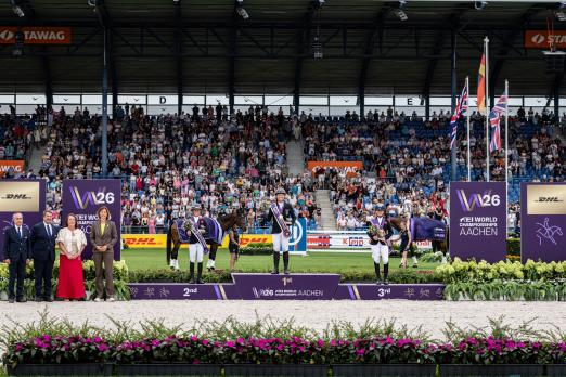 Foto: Die drei Einzel-Medaillengewinner in der Vielseitigkeit (v.l.n.r): Rosalind Canter, Michael Jung und Laura Collet. Links vom Podium (v.l.n.r.): Ingmar De Vos (FEI Präsident and IOC Executive Board Member), David O'Connor (FEI Chair Eventing Committee), Silke Dornik (Sales Director DHL eCommerce) und Stefanie Peters (Präsidentin des ALRV) - Fotograf: ALRV/Jasmin Metzner