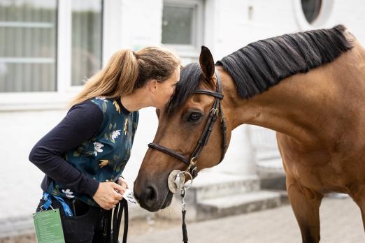 Foto: Pferdepflegerin bei einem wichtigen To Do der täglichen Zusammenarbeit: die Knuddeleinheit - Fotograf: CHIO Aachen/Jasmin Metzner