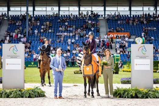 Foto: Das Foto zeigt die Siegerin im Preis des Handwerks, dem Finale der Youngster-Tour beim TSCHIO Aachen 2026, Janika Sprunger aus der Schweiz auf Victory Music Z - gemeinsam mit Marco Herwartz (Präsident der Handwerkskammer Aachen) und ALRV-Präsidentin Stefanie Peters - Fotograf: Jasmin Metzner/CHIO Aachen Foto: Das Foto zeigt die Siegerin im Preis des Handwerks, dem Finale der Youngster-Tour beim TSCHIO Aachen 2026, Janika Sprunger aus der Schweiz auf Victory Music Z - gemeinsam mit Marco Herwartz (Präsident der Handwerkskammer Aachen) und ALRV-Präsidentin Stefanie Peters - Fotograf: Jasmin Metzner/CHIO Aachen
