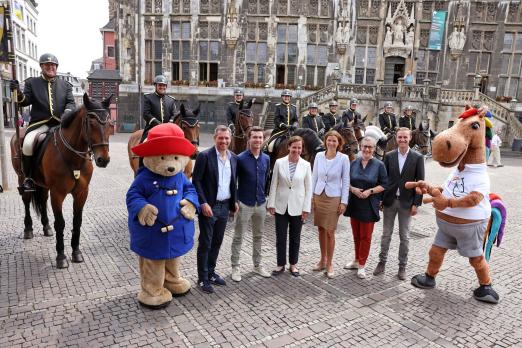 Foto: Die Teilnehmer der Pressekonferenz mit den beiden Maskottchen Karli (r.) und Paddington (l.) vor Mitgliedern der Aachener Stadtreiter. Von links nach rechts: Michael Mronz, Gerrit Nieberg, Birgit Rosenberg, Stefanie Peters, Sibylle Keupen und Sönke Rothenberger - Fotograf: CHIO Aachen/Andreas Steindl