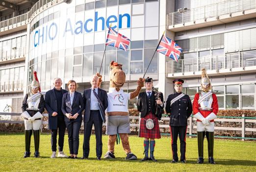 Foto: Vertreter des Partnerlandes Großbritannien, des CHIO Aachen und Maskottchen Karli. Eingerahmt von Guards des Household Cavalry Regiments von links nach rechts: Uwe Brandt, Birgit Rosenberg, Jim Eyre, Karli, Dudelsackspieler David Johnston und Daniel Evans - Fotograf: CHIO Aachen/ Jil Haak